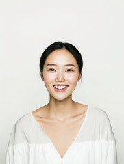 smiling woman with long black hair, wearing white blouse, exudes confidence and warmth against light background. Her joyful expression radiates positivity and approachability
