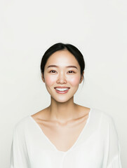 smiling woman with long black hair, wearing white top, exudes confidence and warmth against light background. Her joyful expression radiates positivity and approachability