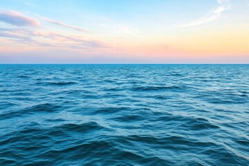 A tranquil view of the ocean at sunset, where soft pink and blue colors fill the sky above gentle rippling waves