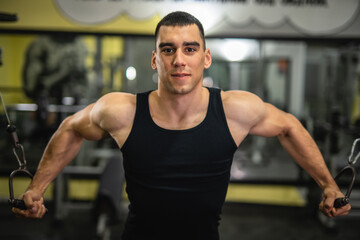 Fototapeta premium portrait of young muscular man do workout on exercise machine at gym