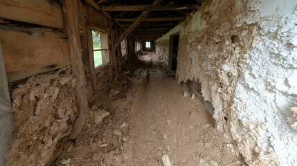 Obraz premium Decaying barn interior, dirt floor, daylight, rural setting, historical architecture
