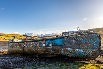 Abandoned and decaying fishing boat wreck blue colored on lakeshore on the Isle of Skye, Scotland,...