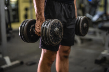 close up on unknown muscular man hold dumbbells in the gym