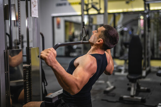 young muscular man do exercise for chest on the exercise cable machine