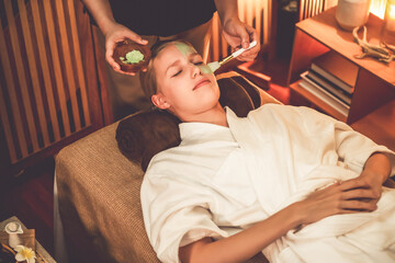 Serene ambiance of spa salon, woman customer indulges in rejuvenating with luxurious face cream massage with warm lighting candle. Facial skin treatment and beauty care concept. Quiescent