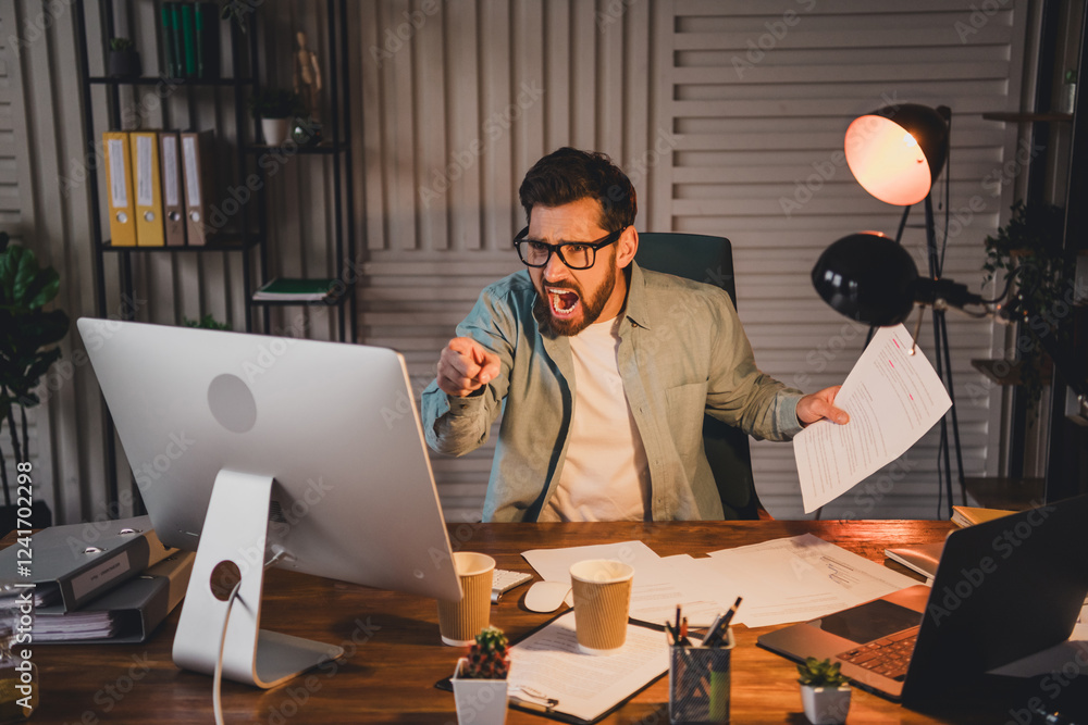 Poster frustrated businessman in a modern office expressing emotion towards computer screen while handling 