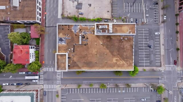 A beautiful overhead view from a drone UAS moving sideways laterally along a large urban city street with various buildings. Overhead nadir view from moving dolly motion aerial drone UAS.