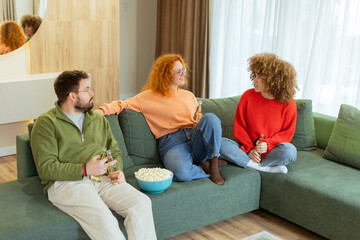 Friends enjoying a cozy evening with drinks and popcorn in a stylish living room filled with...