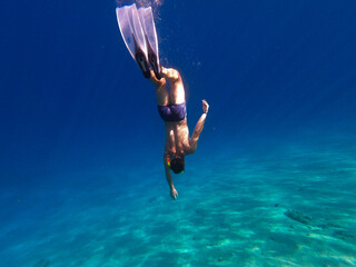 Man swims in flippers in blue sea