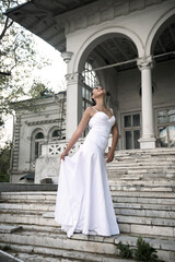 Obraz premium elegant girl in a long white dress on the steps of a marble building of the 18th century