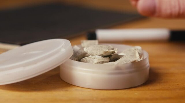 Snus nicotine tobacco close up, pack of tobacco for gum. unhealthy addiction. Man opening box with snus and taking one. 