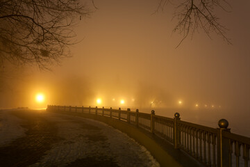 city embankment illuminated by lanterns in the night fog