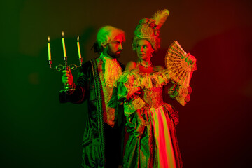 Elegant masquerade couple dressed in vintage costumes posing under dramatic lighting on a...