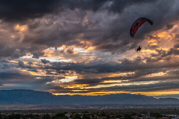 USA, New Mexico, Sandia Mountains. Cloudy sunrise over Albuquerque and hang glider.