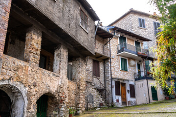 Wide cobblestone alley lined with old medieval stone houses with arched porches on a gray winter day