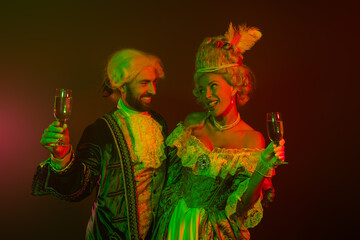 Fototapeta premium Elegant couple dressed in royal vintage costumes enjoying a festive celebration with drinks
