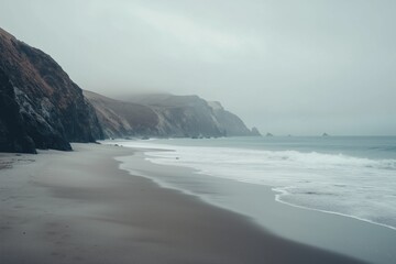 Misty coastal cliffs and tranquil ocean waves in overcast light