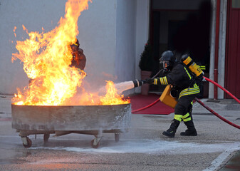 firefighter drill wearing respirator and oxygen tank extinguishing fire with foam
