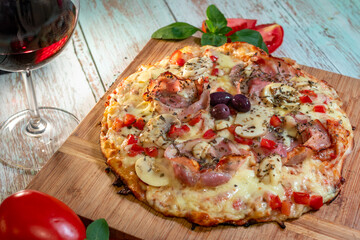 Pizza with mozzarella and parma mushroom filling with glass of wine and tomato in the background