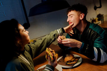 Multiracial couple enjoying burgers together on valentine's day in a cozy restaurant