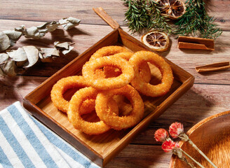 Crispy Fried Golden Onion Rings serve in wooden tray isolated on wooden table side view taiwan snack food