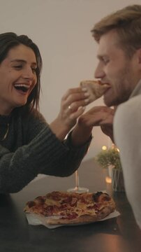 Couple enjoys pizza and wine during a romantic dinner at home.