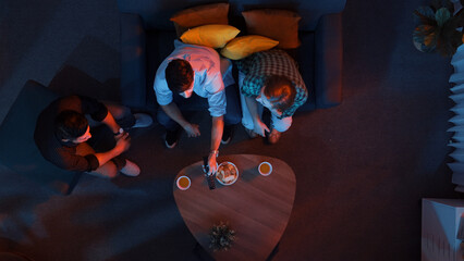 Top aerial view of caucasian father and mother watching movie while eating snack with friend. Happy...
