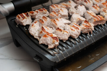 pork is fried on a modern electric grill in the kitchen close-up
