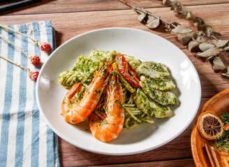 Seafood Pesto Pasta with Shrimp and grilled fish topped green pesto sauce served in plate isolated on wooden table side view of taiwan food