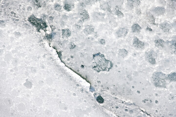 Nature’s artistry is visible in intricate ice fractures on the water surface of the lake