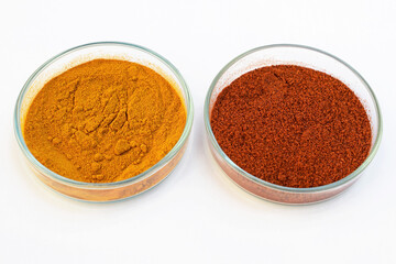 Turmeric powder and paprika (ground red pepper) in a petri dish, white background