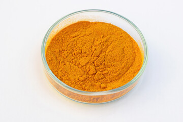 Turmeric powder in a petri dish, white background