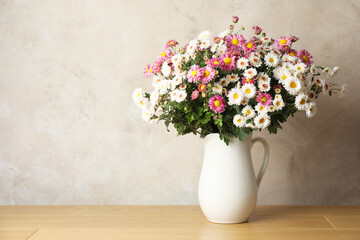 Vase with beautiful flowers on pink wooden table, space for text