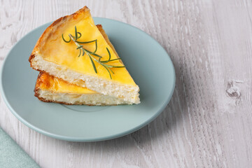 Delicious cottage cheese casserole served on a light blue plate with a sprig of rosemary accent