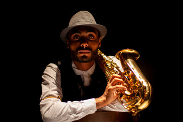 Musician with saxophone. Serious face portrait on black background. Low key.