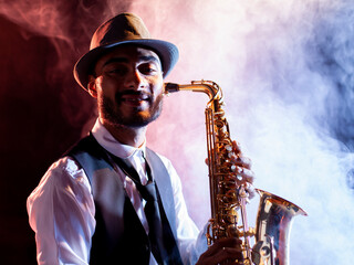 Smiling saxophonist with hat and smoke on background
