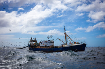 Fishing trawler conducts commercial fishing for fish and seafood in the ocean before the start of storm.