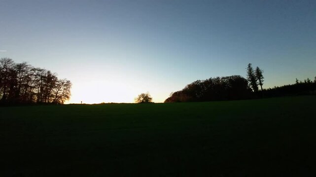 Cinematic Drone Shot of a Sunset Over fluffy clouds ontop of green hills 