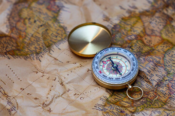 Antique brass compass resting on a world map, symbolizing travel and adventure.