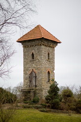 Obraz premium Stone tower with a red tiled roof in Tetele, Jelgava, Latvia. Historic landmark in a rural setting