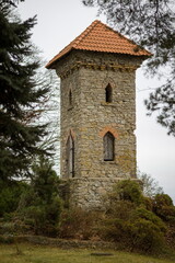 Obraz premium Stone tower with a red tiled roof in Tetele, Jelgava, Latvia. Historic landmark in a rural setting