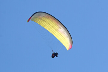 Tandem Paraglider flying in a blue sky	