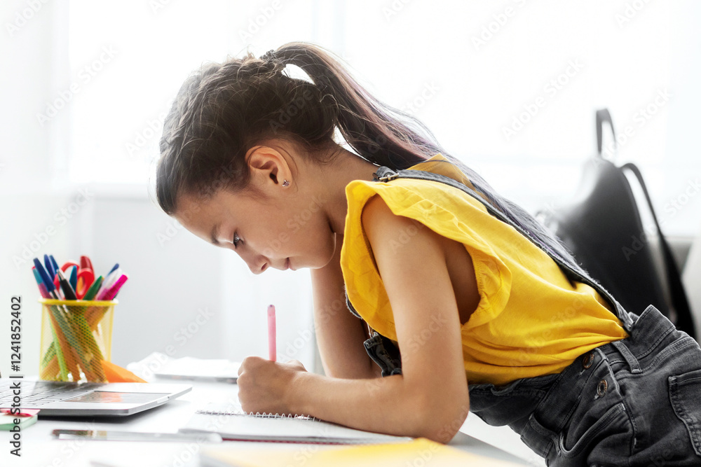 Aufkleber Distant Studying. Side view profile of focused little student writing down information watching webinar on laptop with empty screen, free space mock up. Youth making home assignment for online class