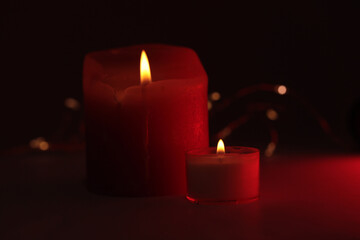 Soft focus. smoke blur Burning Candles in dark. Evening, night Light and shadow red, black background. Minimalist still life.