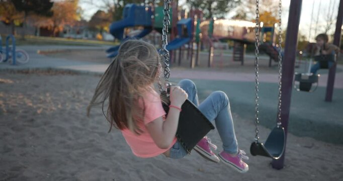 Girl Spinning on Swingset in Park