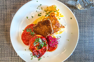 Stuffed Spicy Bell Peppers Rocoto Relleno, salsa, garnish, potato gratin in white plate in restaurant. Colorful Traditional Peruvian Food. toStuffed Spicy Bell Peppers Rocoto Relleno, down view, close