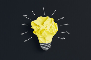 Light bulb made of crumpled yellow paper representing creative idea on black background. Creative light bulb idea with paper and hand drawn arrows around it