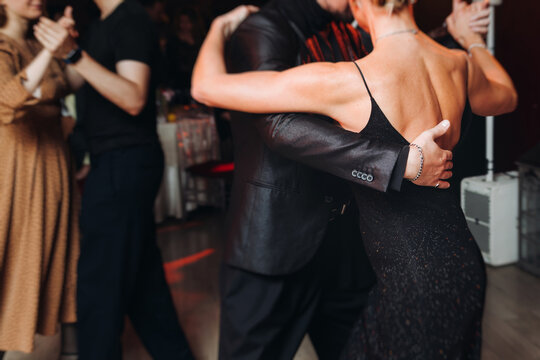 Couples dancing traditional latin argentinian dance milonga in the ballroom, tango salsa bachata kizomba lesson in red and purple lights, performance rehearsal, evening dance school class festival