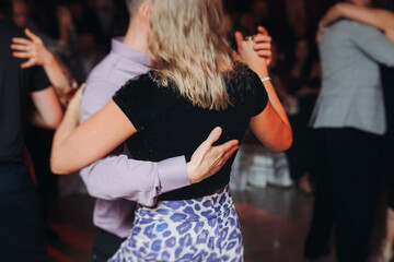 Couples dancing traditional latin argentinian dance milonga in the ballroom, tango salsa bachata kizomba lesson in red and purple lights, performance rehearsal, evening dance school class festival
