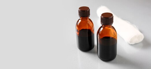 Bottles of iodine and gauze roll on grey background with space for text
